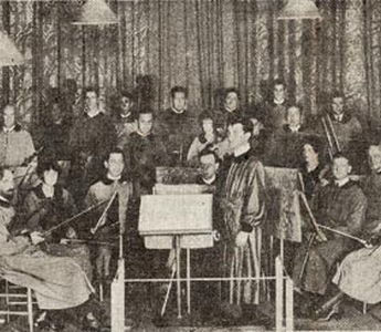 One of the early pictures of the Community Arts String Orchestra in costumes designed by Adele Herter, Roger Clerbois at the conductor’s stand. Concertmaster is Anthony van der Voort; first ‘cello, Harry Kaplun; second ‘cello, Roscoe Lyans; first desk, second violins, Margaret Ellison (now Mrs. Roy C. Beckman of Florida;) behind her is Fred Greenough, violinist; and seated behind her husband is Mrs. Clerbois, violist. The harpist is Mrs. Lyans. An early record of the orchestra personnel says 12 were professionals and the other nine “consisted of two students, a gardener, a taxi driver, a bank president’s wife, a horticulturist, a curio shop keeper and a chemist.” 